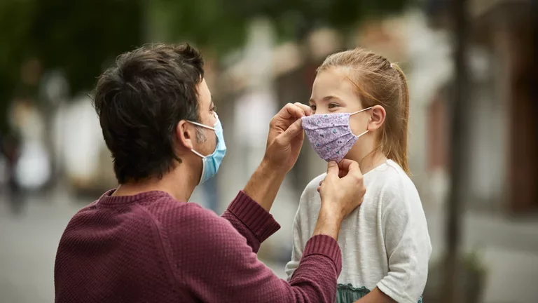 Father Putting Home Made Face Mask on Little Daughter